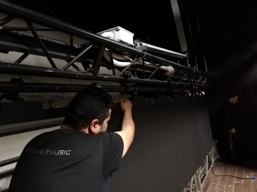 Tecnico al montaggio di proiettori su americana
